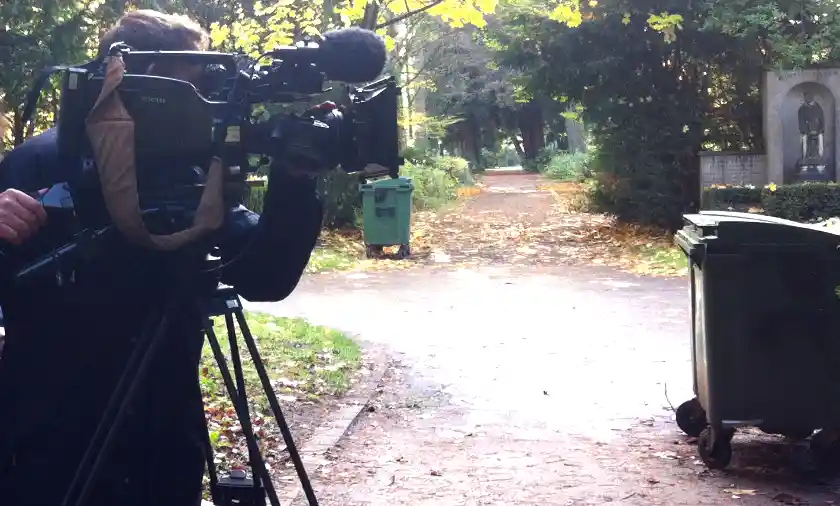 Fotografieren auf Friedhöfen Ein Kameramann filmt durch eine Fernsehkamera eine Szene auf einem Friedhof